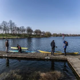 Menschen am Bootssteg mit Kajaks